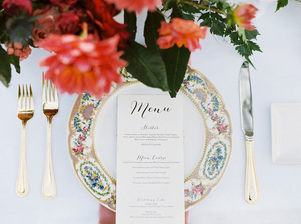 Wedding reception place setting with gold flatware with floral Charles Sadek Sevres china and menu card