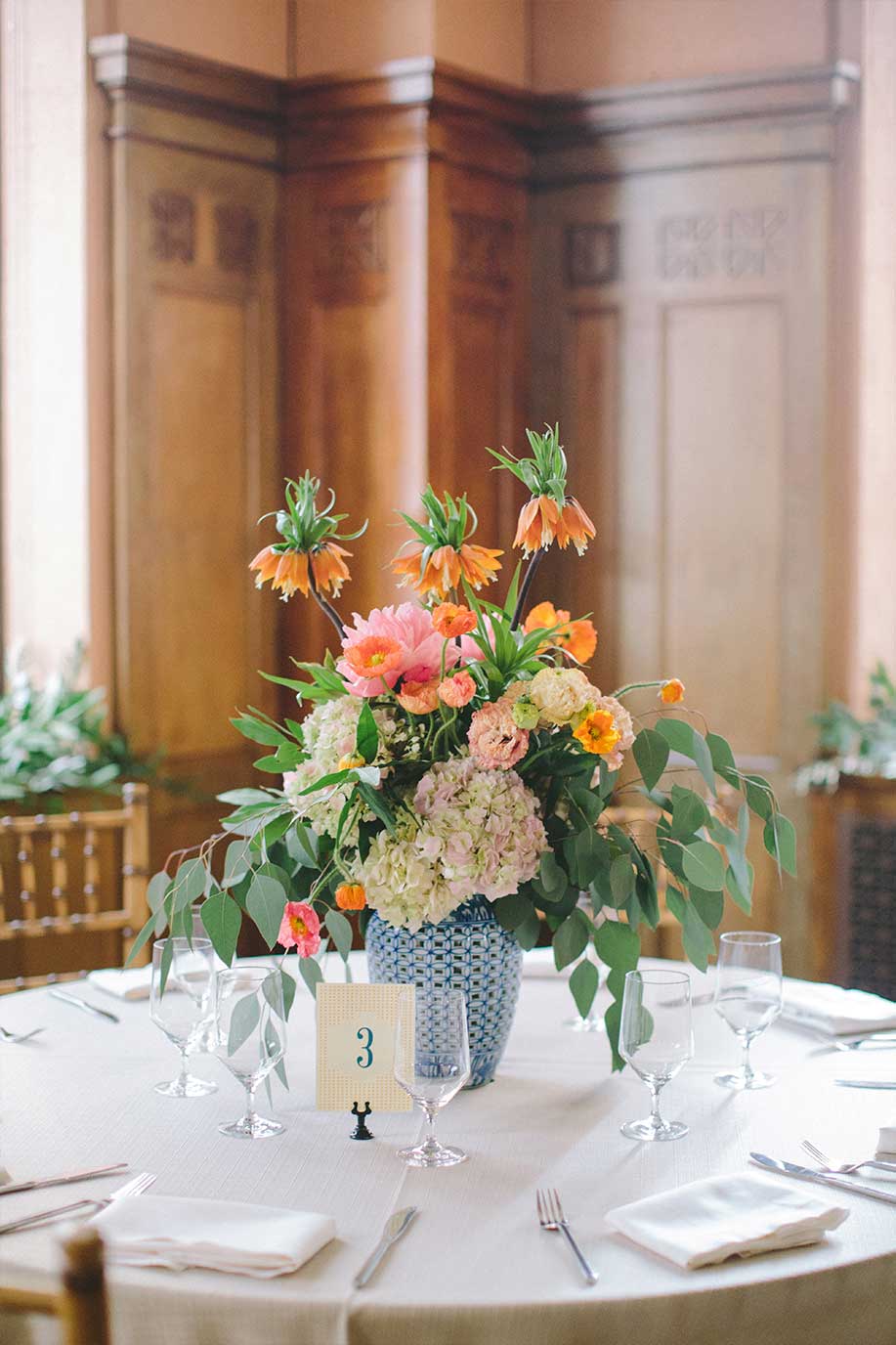 Wedding floral centerpiece in blue and white porcelain vase and table number card