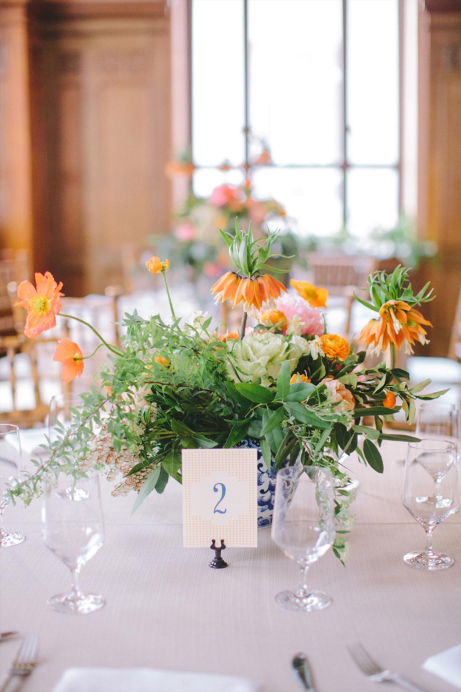 Wedding floral centerpiece in blue and white porcelain vase and table number card