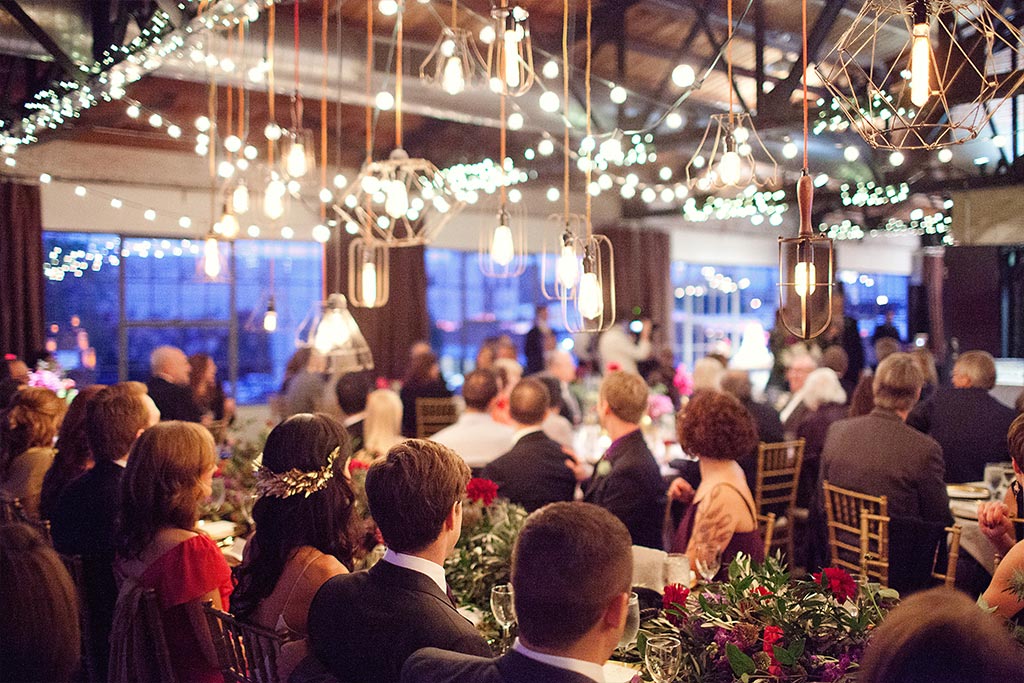 Wedding reception long head table with industrial cage lights and floral garland at Hickory Street Annex in Dallas