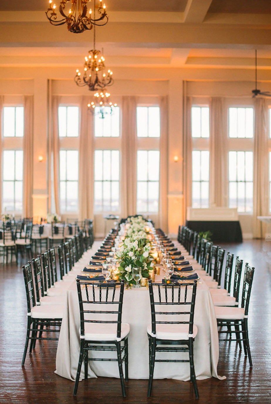 Long head table with floral garland and candles at wedding reception at The Room on Main in Dallas, Texas