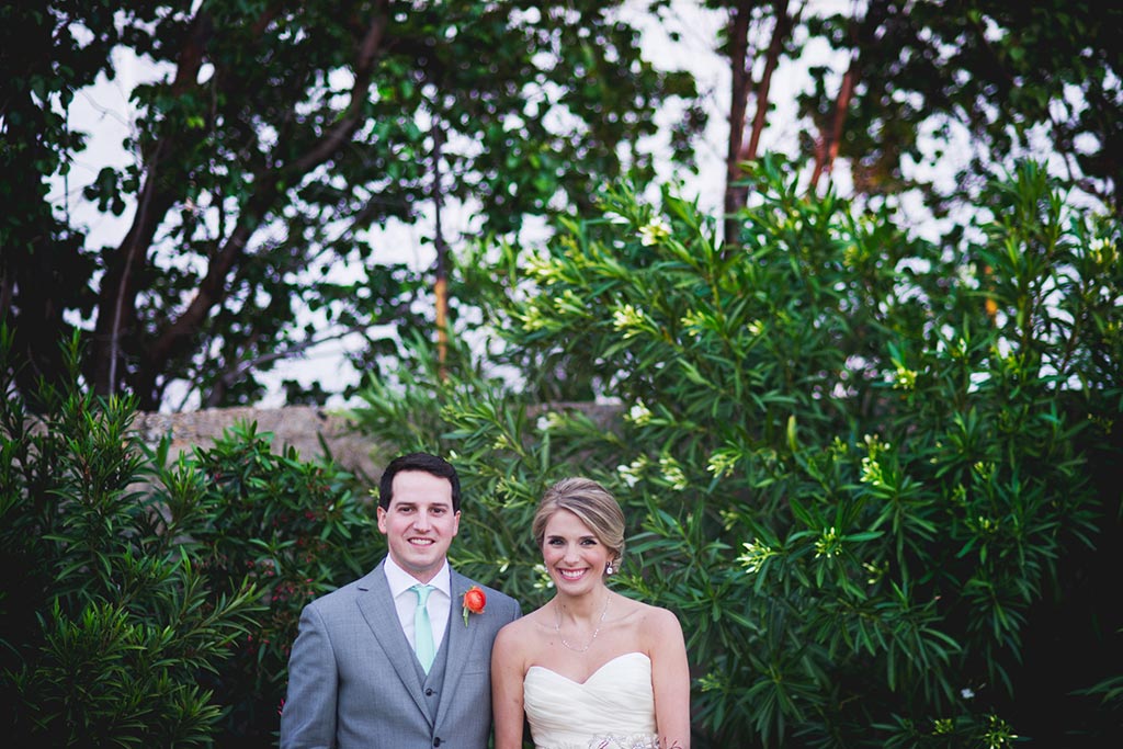 Bride and groom take a wedding day portrait in front of greenery at Hickory Street Annex in Dallas