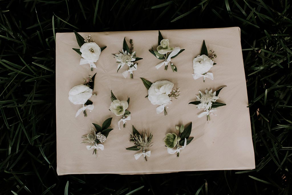 White ranunculus boutonniere for groomsmen